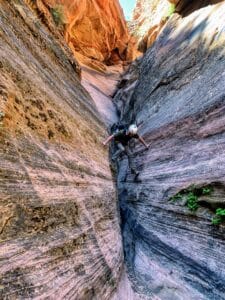 A climber enters a challenging but beautiful portion of a slot canyon in Powell's Way